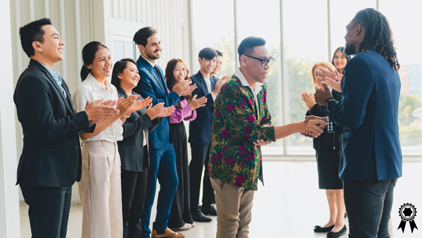 Award winning shaking hands while co-workers applaud. Award winning shaking hands while co-workers applaud.